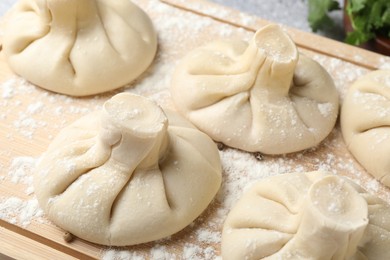 Photo of Uncooked khinkalis (dumplings) on wooden board, closeup