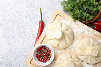Photo of Uncooked khinkalis (dumplings) and spices on light table, flat lay. Space for text
