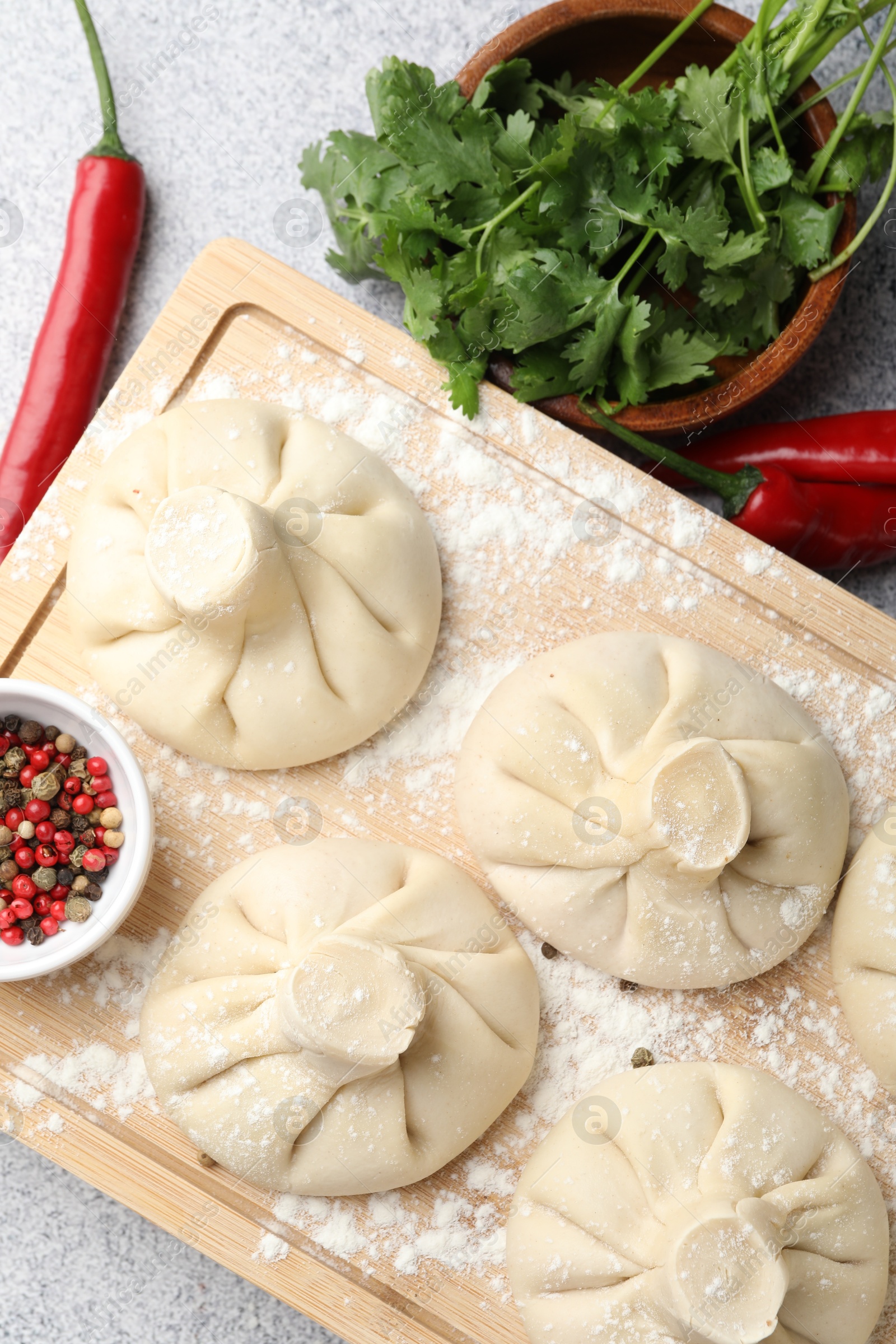Photo of Uncooked khinkalis (dumplings) and spices on light table, flat lay