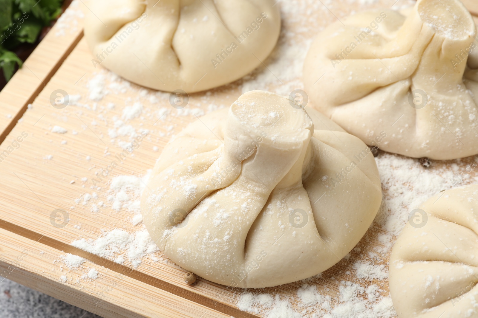 Photo of Uncooked khinkalis (dumplings) on wooden board, closeup