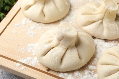 Photo of Uncooked khinkalis (dumplings) on wooden board, closeup