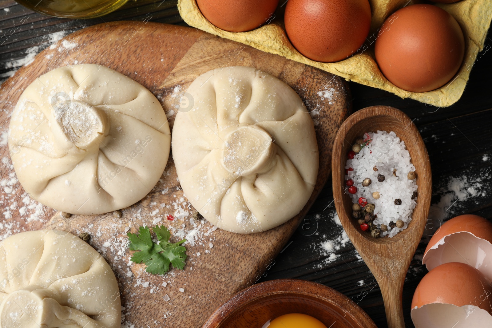 Photo of Uncooked khinkalis (dumplings) and ingredients on wooden table, flat lay