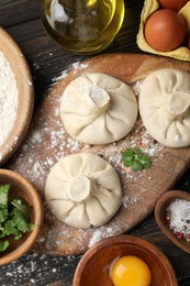 Photo of Uncooked khinkalis (dumplings) surrounded by ingredients on wooden table, flat lay