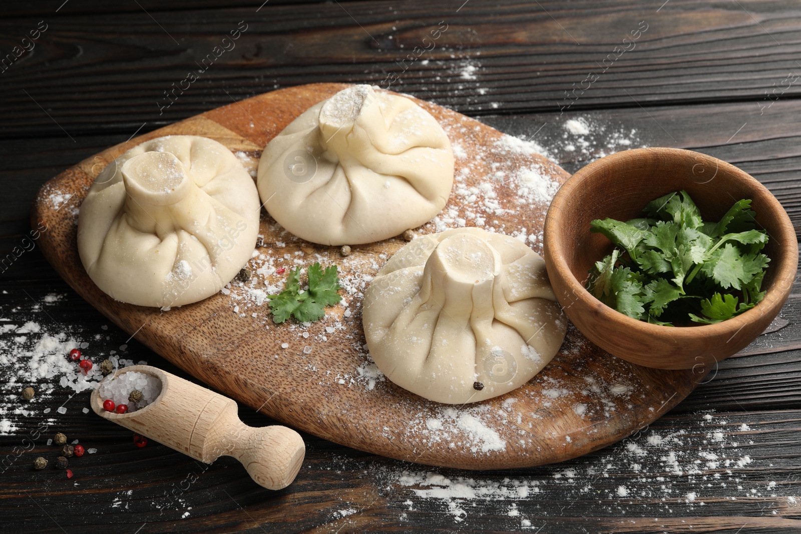 Uncooked khinkalis (dumplings), spices and parsley on dark wooden table, closeup Photo of Uncooked khinkalis (dumplings), spices and parsley on dark wooden table, closeup