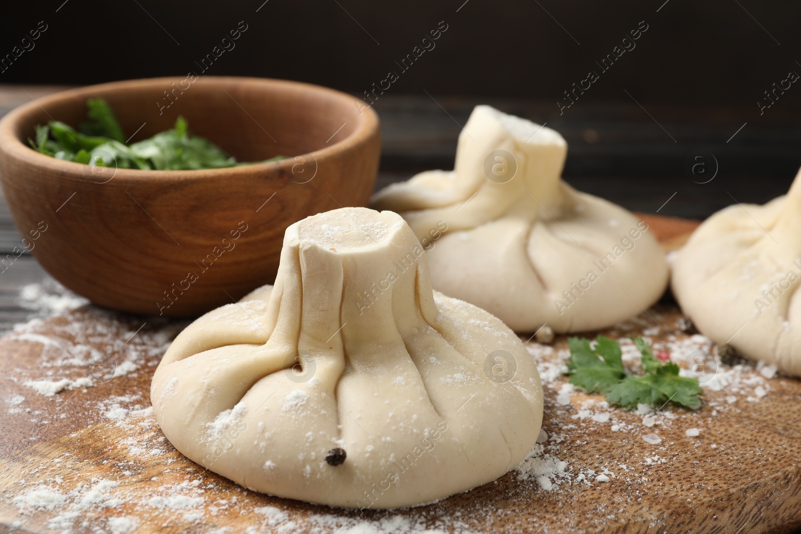 Uncooked khinkalis (dumplings), spices and parsley on wooden board, closeup Photo of Uncooked khinkalis (dumplings), spices and parsley on wooden board, closeup