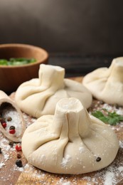 Photo of Uncooked khinkalis (dumplings) with spices on wooden board, closeup
