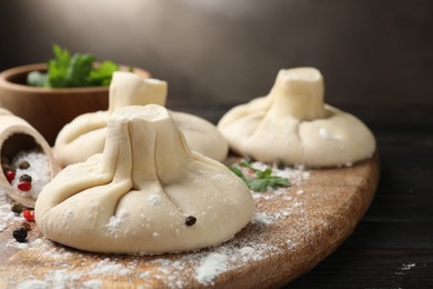 Photo of Uncooked khinkalis (dumplings) with spices on wooden table, closeup