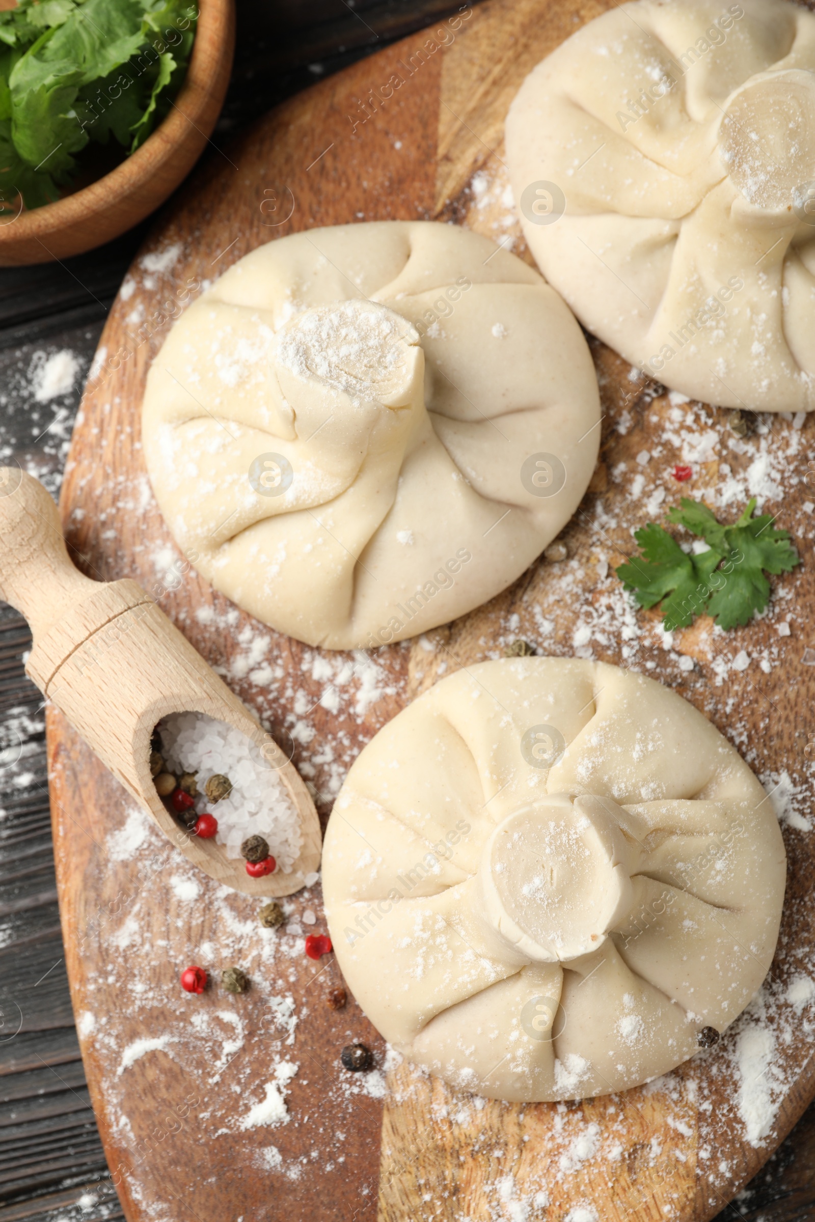 Uncooked khinkalis (dumplings) with spices and parsley on wooden table, flat lay Photo of Uncooked khinkalis (dumplings) with spices and parsley on wooden table, flat lay