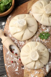 Photo of Uncooked khinkalis (dumplings) with spices and parsley on wooden table, flat lay