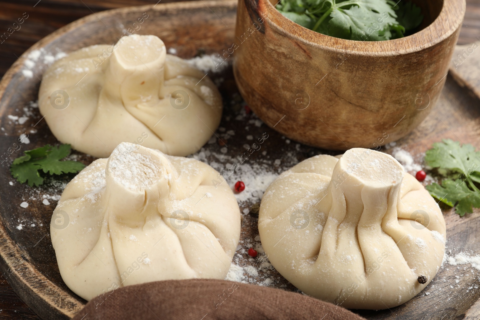 Uncooked khinkalis (dumplings) with peppercorns and parsley on table, closeup Photo of Uncooked khinkalis (dumplings) with peppercorns and parsley on table, closeup