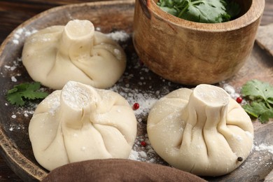 Photo of Uncooked khinkalis (dumplings) with peppercorns and parsley on table, closeup