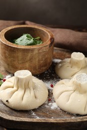 Photo of Uncooked khinkalis (dumplings) with peppercorns and parsley on table, closeup