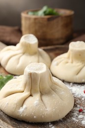 Photo of Uncooked khinkalis (dumplings) on wooden table, closeup