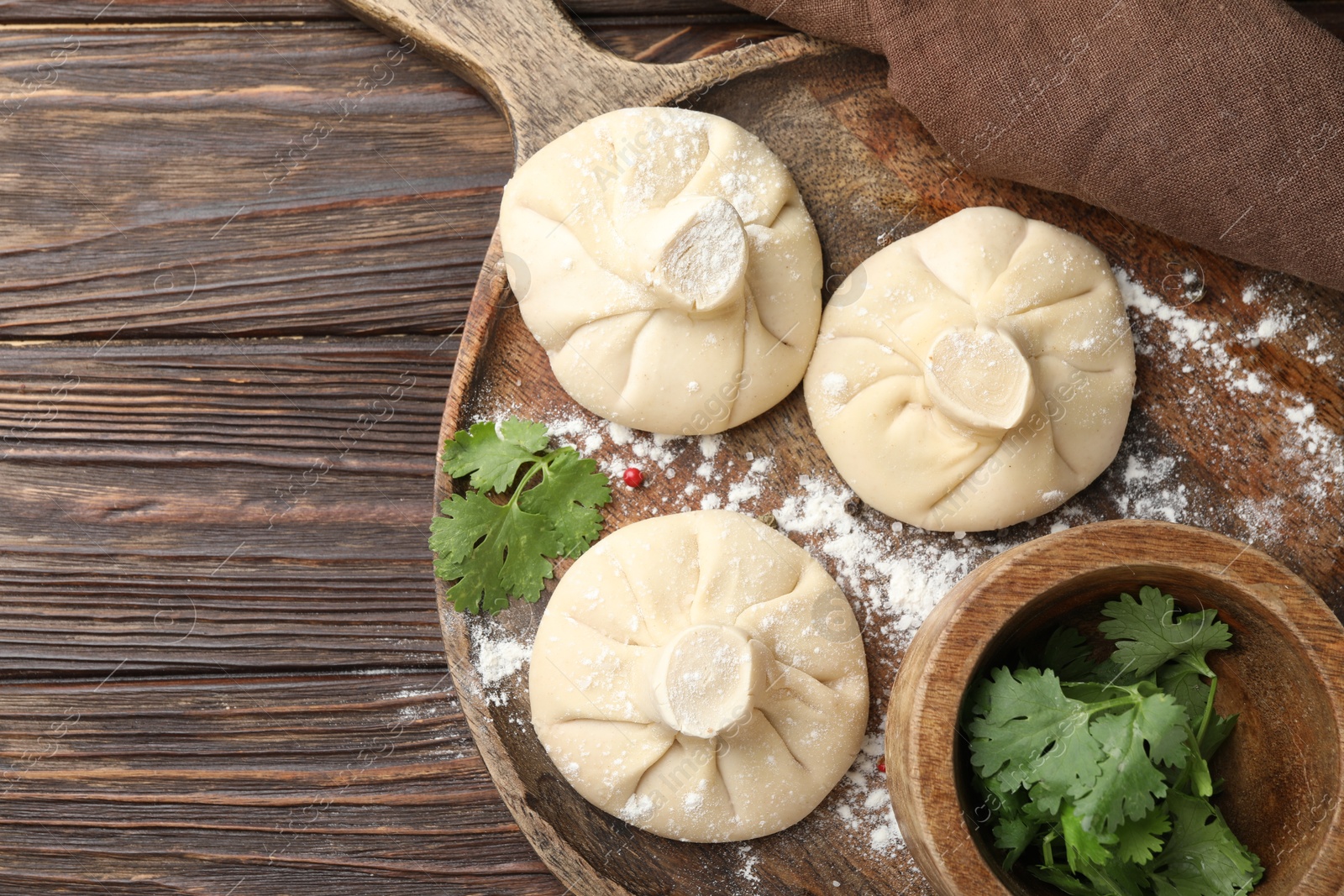 Uncooked khinkalis (dumplings) and parsley on wooden table, top view. Space for text Photo of Uncooked khinkalis (dumplings) and parsley on wooden table, top view. Space for text