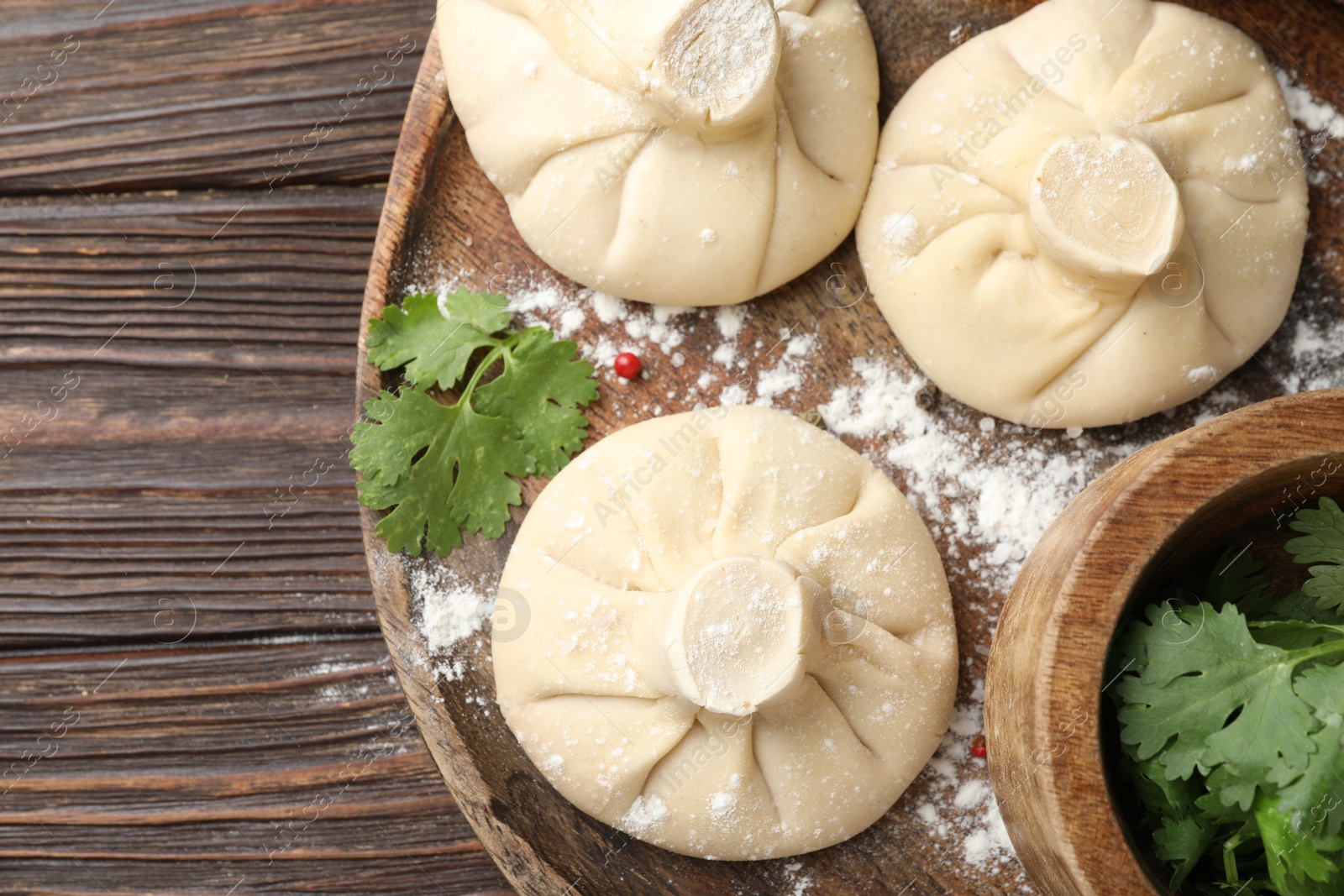 Uncooked khinkalis (dumplings) and parsley on wooden table, top view Photo of Uncooked khinkalis (dumplings) and parsley on wooden table, top view
