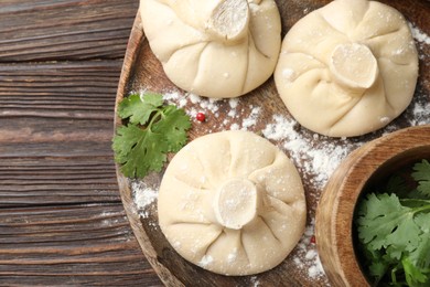 Photo of Uncooked khinkalis (dumplings) and parsley on wooden table, top view