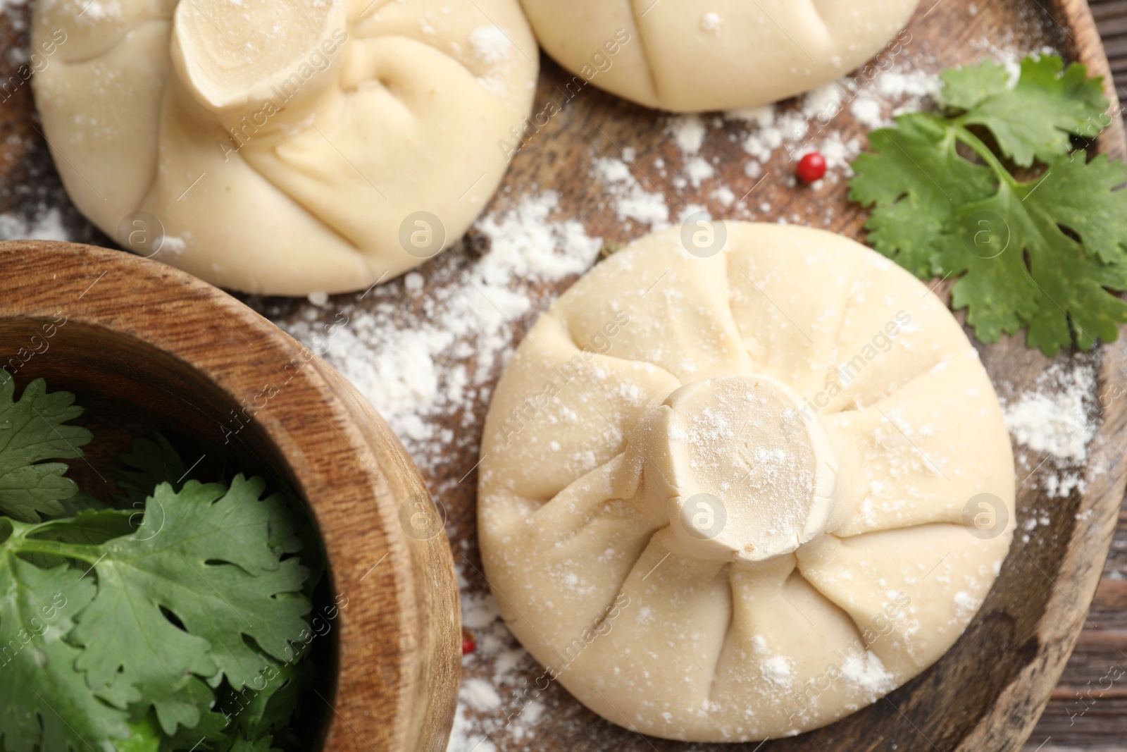 Uncooked khinkalis (dumplings) and parsley on wooden table, top view Photo of Uncooked khinkalis (dumplings) and parsley on wooden table, top view