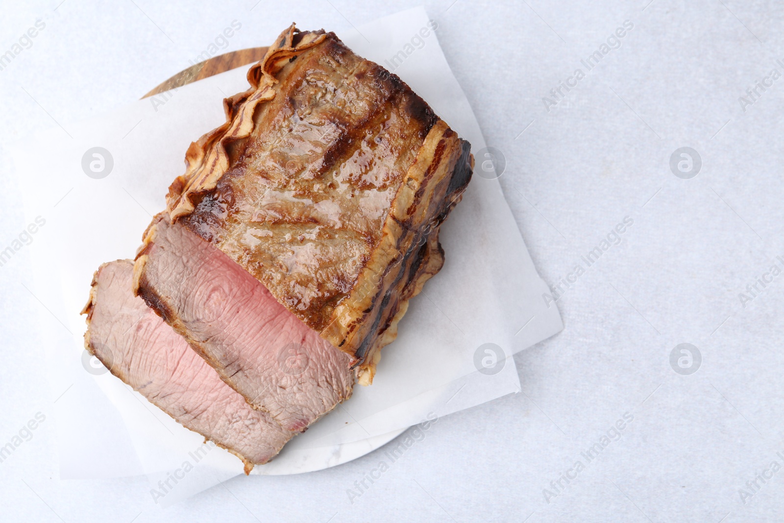 Delicious baked beef meat on light table, top view. Space for text Photo of Delicious baked beef meat on light table, top view. Space for text