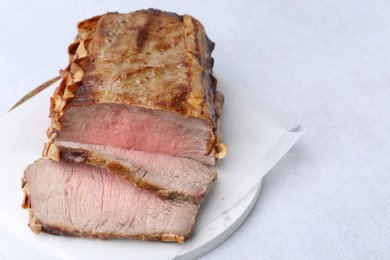 Photo of Delicious baked beef meat on light table, closeup. Space for text