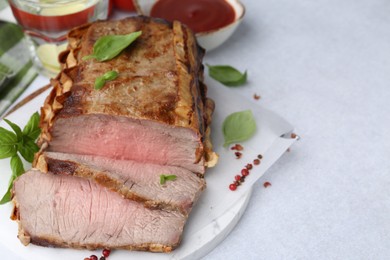 Photo of Delicious baked beef meat, spices and water with lime on light table, closeup. Space for text