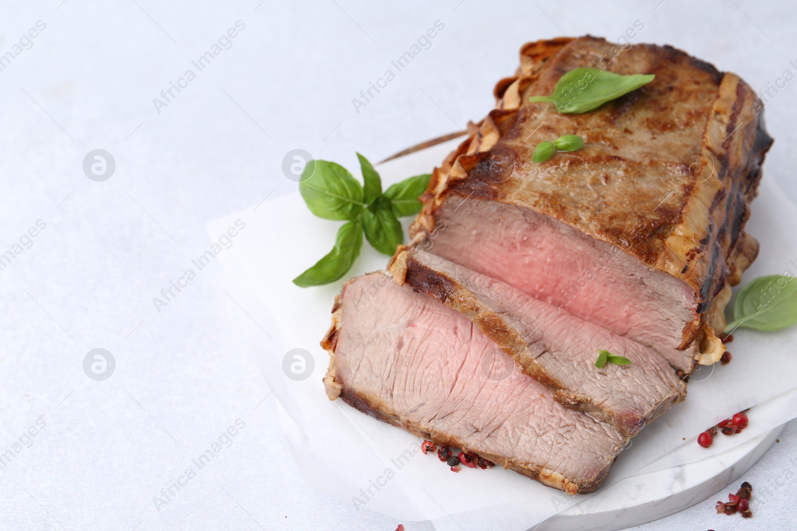 Photo of Delicious baked beef meat and spices on light table, closeup. Space for text