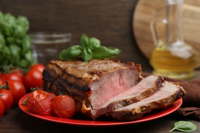 Photo of Delicious baked beef meat, tomatoes and basil on table, closeup