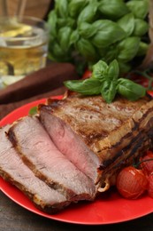 Photo of Delicious baked beef meat, tomatoes and basil on table, closeup