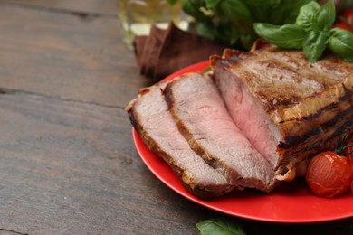 Photo of Delicious baked beef meat, tomatoes and basil on wooden table, closeup. Space for text