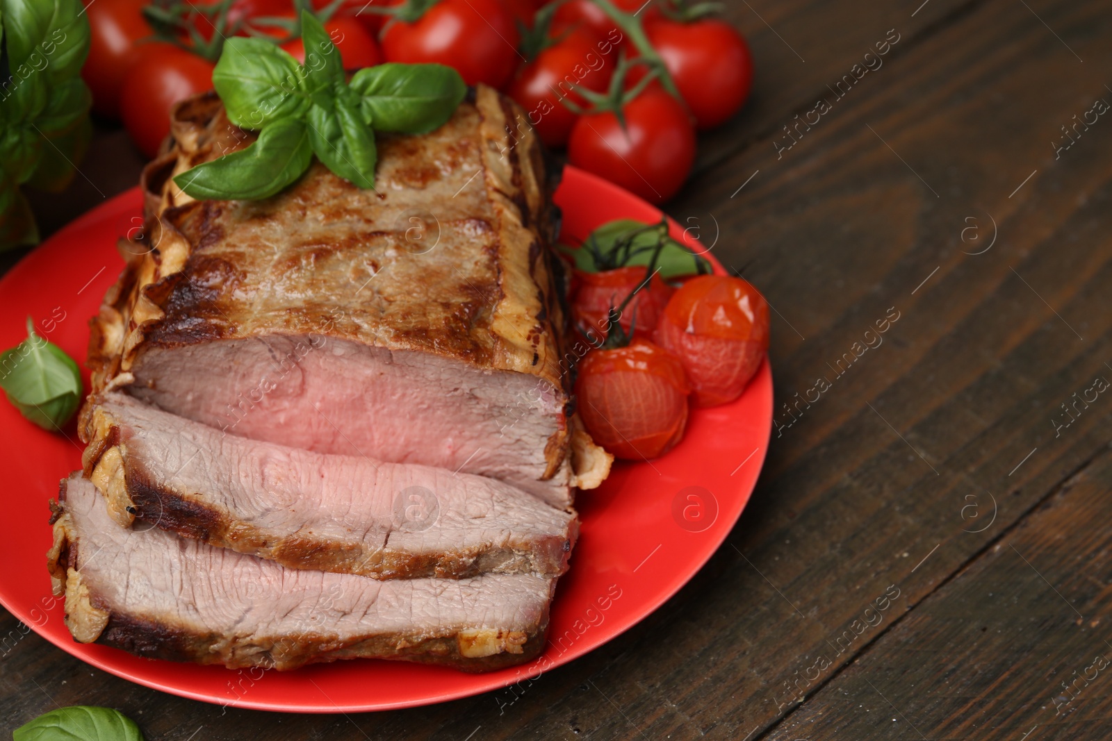 Photo of Delicious baked beef meat, tomatoes and basil on wooden table, closeup. Space for text