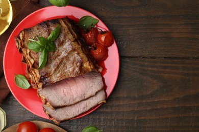 Photo of Delicious baked beef meat, tomatoes and basil on wooden table, flat lay. Space for text