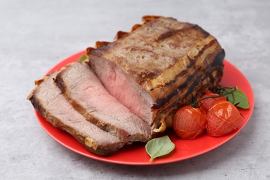 Photo of Delicious baked beef meat, tomatoes and basil on grey table, closeup