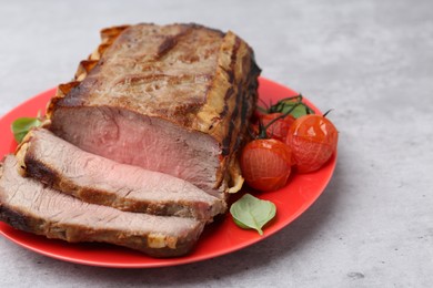 Photo of Delicious baked beef meat, tomatoes and basil on grey table, closeup. Space for text