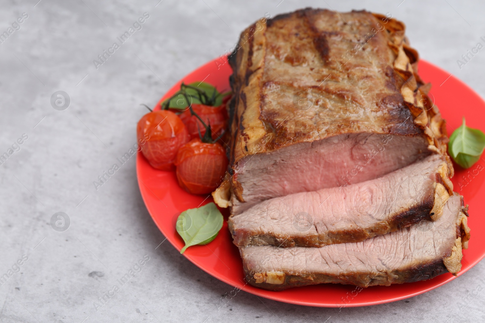 Photo of Delicious baked beef meat, tomatoes and basil on grey table, closeup. Space for text