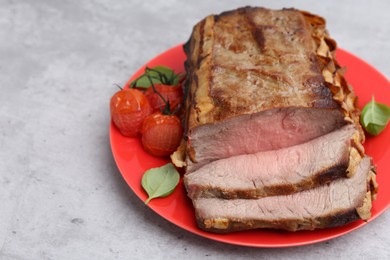 Photo of Delicious baked beef meat, tomatoes and basil on grey table, closeup. Space for text