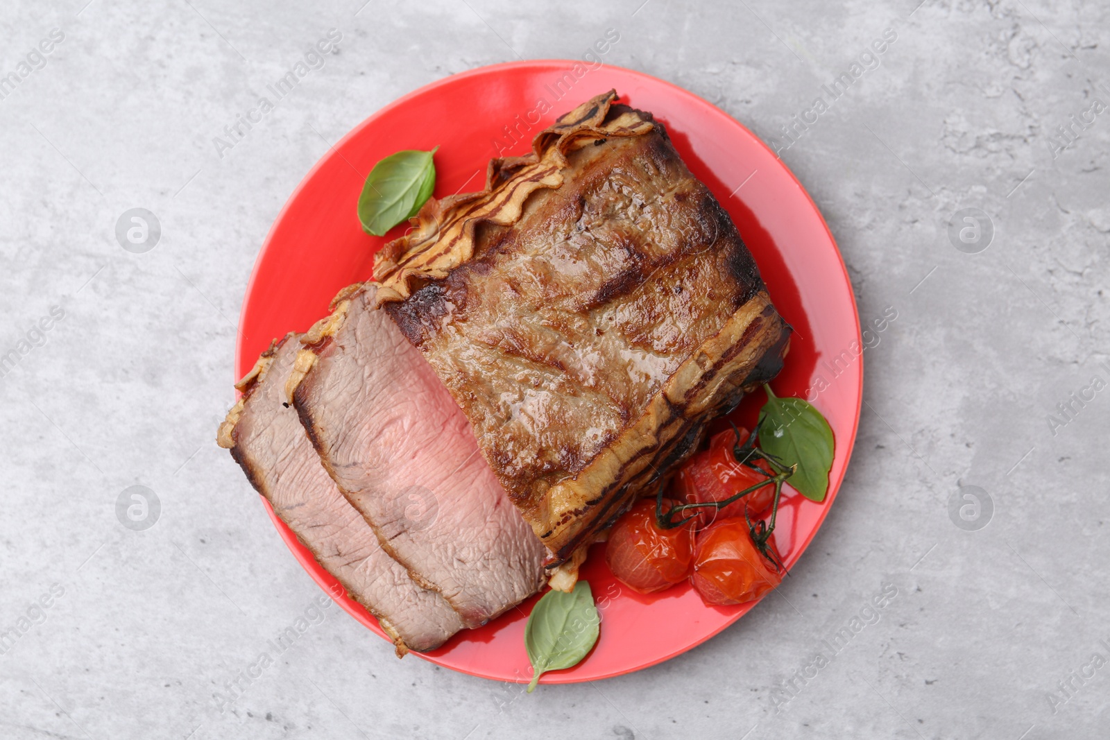 Photo of Delicious baked beef meat, tomatoes and basil on grey table, top view