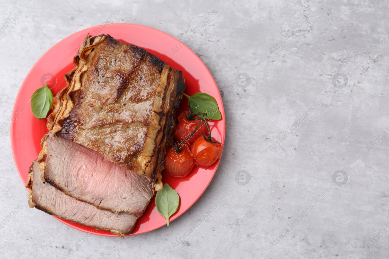 Photo of Delicious baked beef meat, tomatoes and basil on grey table, top view. Space for text