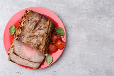 Photo of Delicious baked beef meat, tomatoes and basil on grey table, top view. Space for text