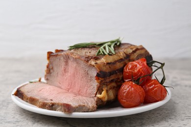 Photo of Delicious baked beef meat, tomatoes and rosemary on grey table, closeup