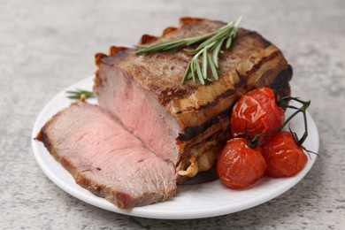 Photo of Delicious baked beef meat, tomatoes and rosemary on grey table, closeup