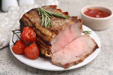 Photo of Delicious baked beef meat, tomatoes, rosemary and sauce on grey table, closeup