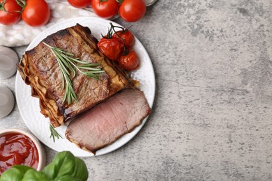 Photo of Delicious baked beef meat, tomatoes, basil, rosemary and sauce on grey table, flat lay. Space for text