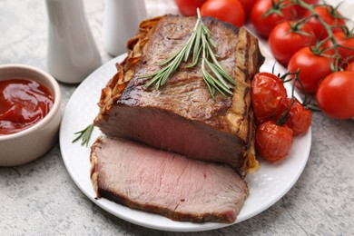 Photo of Delicious baked beef meat, tomatoes, rosemary and sauce on grey table, closeup