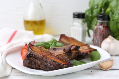 Photo of Roasted beef ribs, tomatoes and spices on white wooden table, closeup
