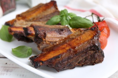 Photo of Roasted beef ribs, tomatoes and basil on table, closeup