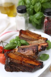 Photo of Roasted beef ribs, tomatoes and spices on table, closeup