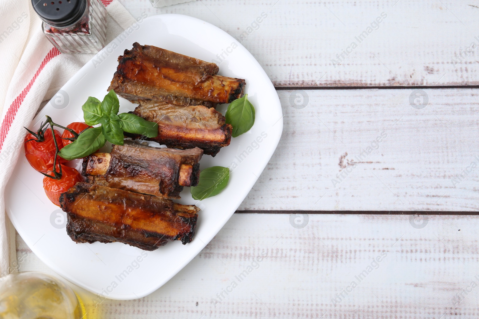 Roasted beef ribs, tomatoes and spices on white wooden table, flat lay. Space for text Photo of Roasted beef ribs, tomatoes and spices on white wooden table, flat lay. Space for text