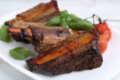 Photo of Roasted beef ribs, tomatoes and basil on table, closeup