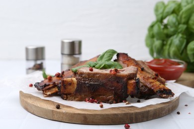 Photo of Roasted beef ribs with spices and ketchup on white table, closeup
