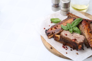 Photo of Roasted beef ribs with spices and ketchup on white tiled table, closeup. Space for text