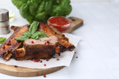 Photo of Roasted beef ribs with spices and ketchup on white tiled table, closeup. Space for text